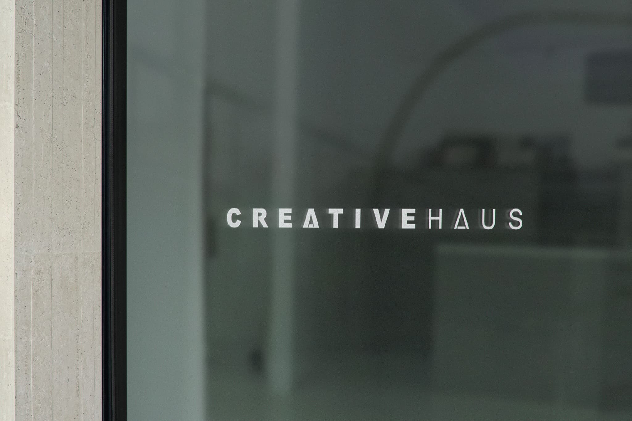 CREATIVEHAUS wordmark applied to a dark glass entrance.